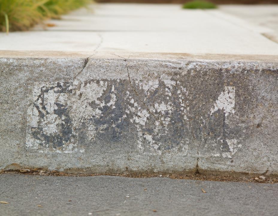 An old faded curb address number with chipped paint